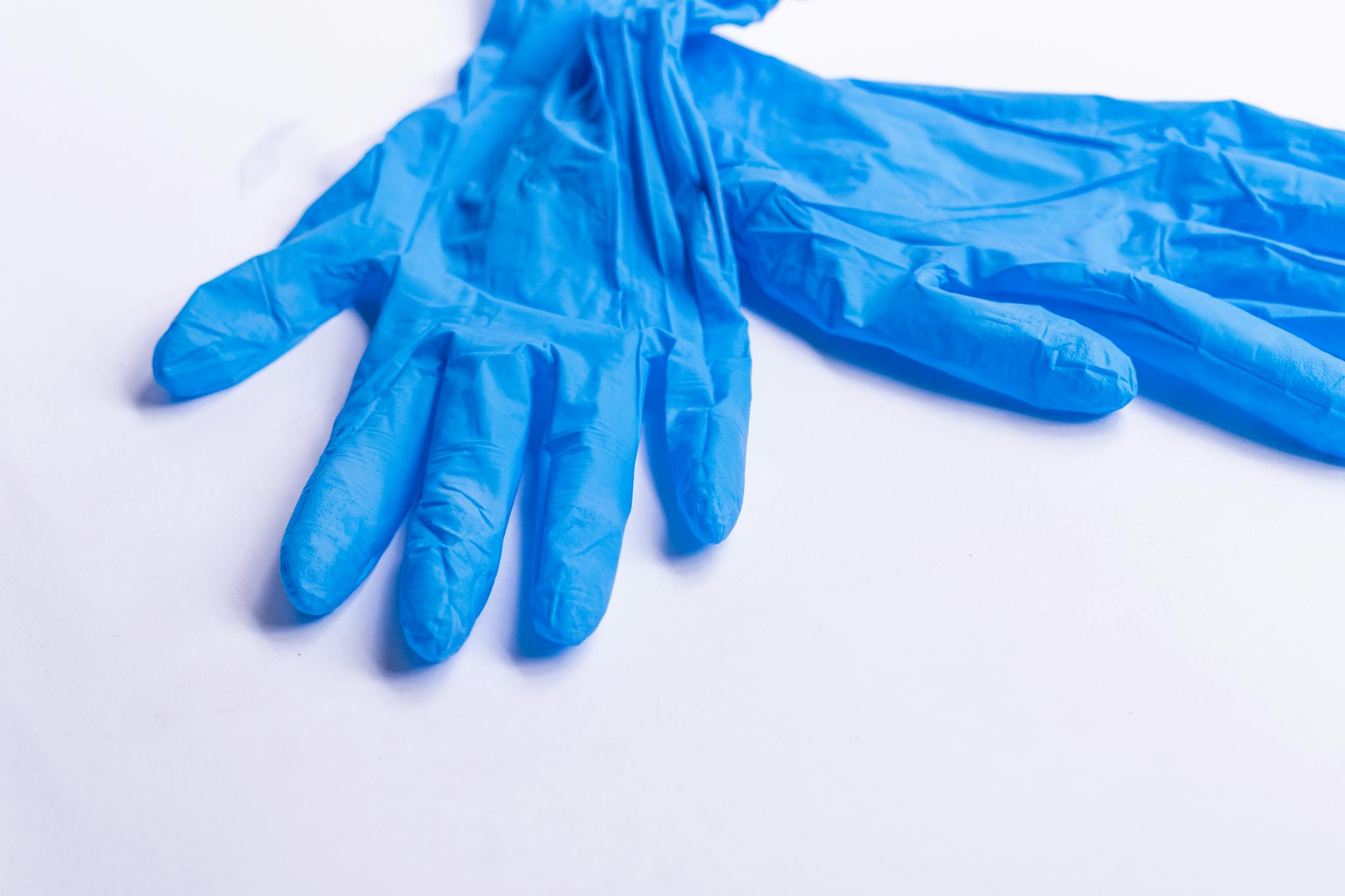 Pair of blue nitrile disposable gloves resting on a clean white surface.